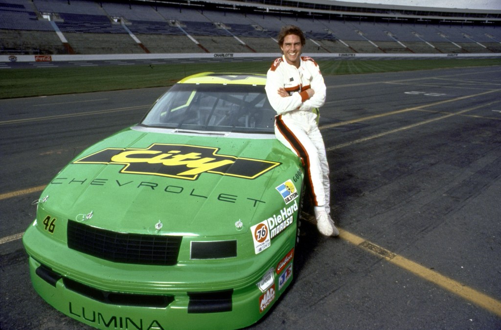 Tom Cruise leans on the lime green number 46 Chevrolet City Lumina.