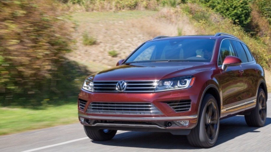 A brown Volkswagen Touareg midsize SUV is driving on the road.