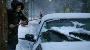 A woman clears snow from her car during a storm in Newton, MA, on December 05, 2020.