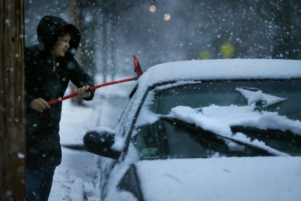 A woman clears snow from her car during a storm in Newton, MA, on December 05, 2020.
