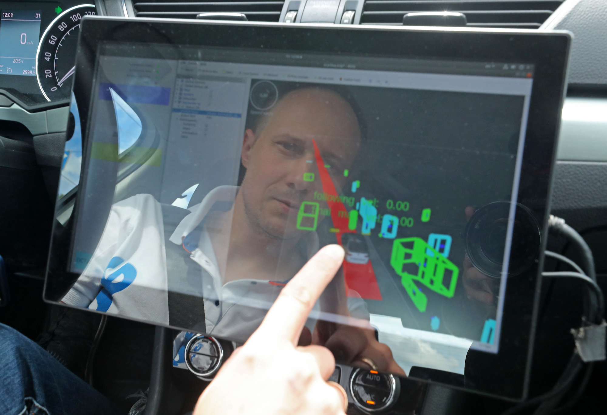 A man's reflection is seen a car touchscreen