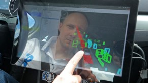 A man's reflection is seen a car touchscreen