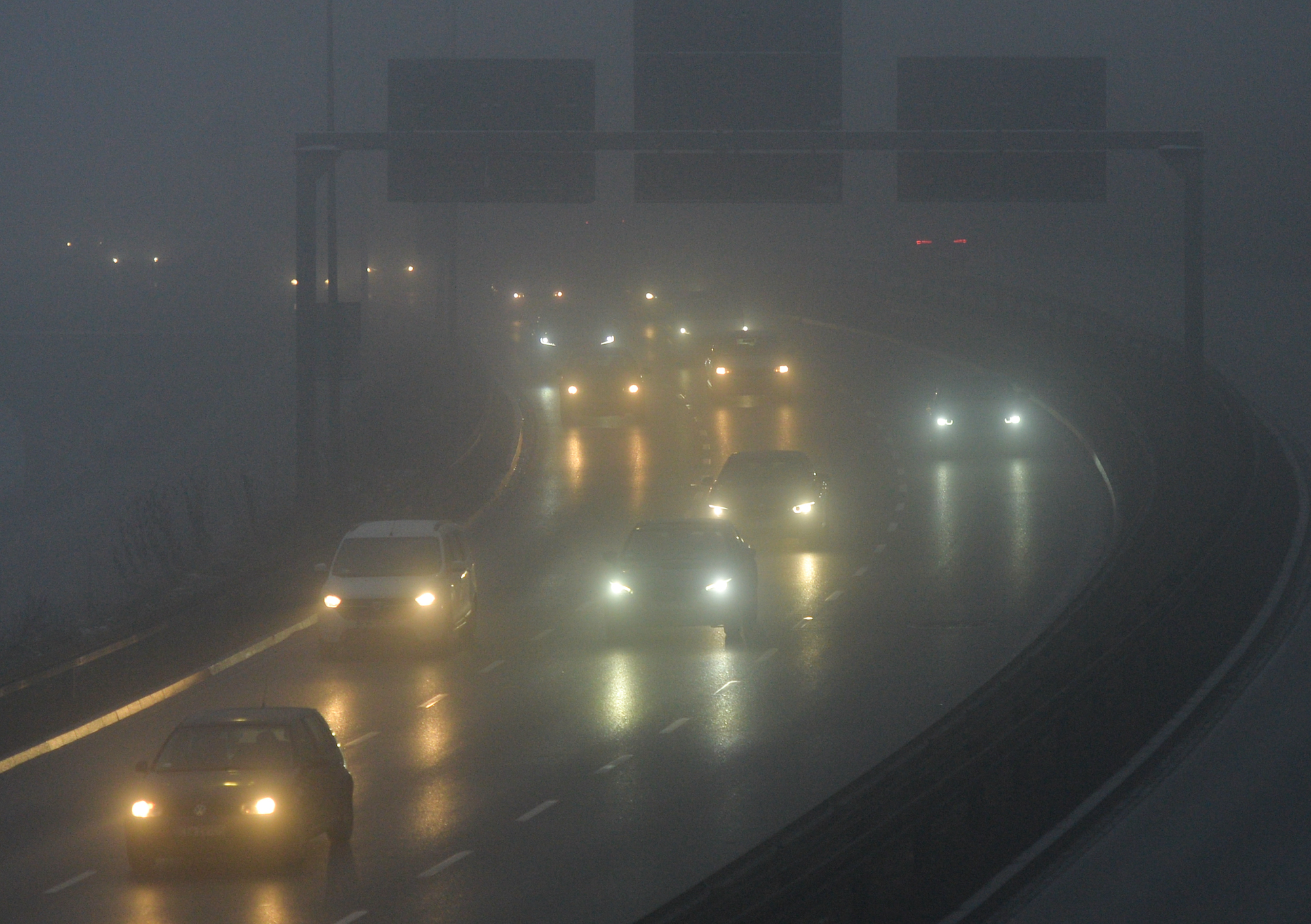 Cars' headlights can be seen through snow and fog on a highway