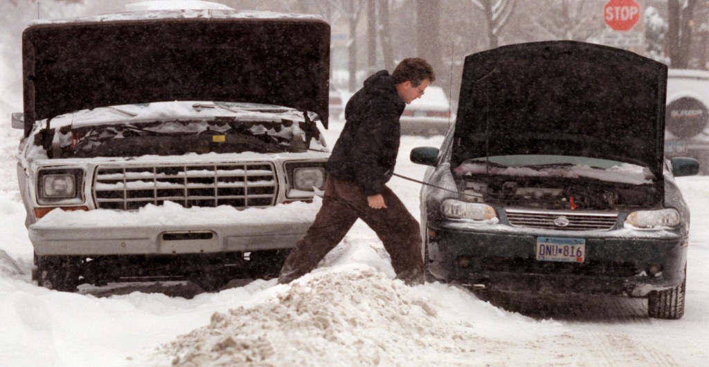 man jumping a car battery in the snow