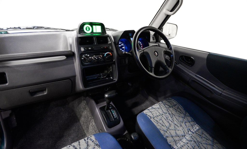The gray dashboard and blue-and-silver front seats of a 1995 Mitsubishi Pajero Mini VR-II
