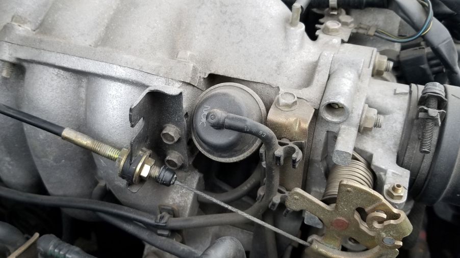 The intake manifold, throttle body, and throttle cable of a 1999 Mazda MX-5 Miata