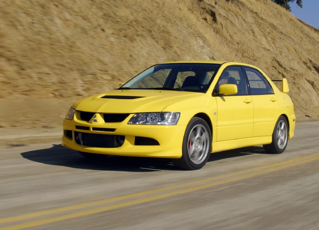 A yellow 2003 Mitsubishi Lancer Evolution VIII on a canyon road