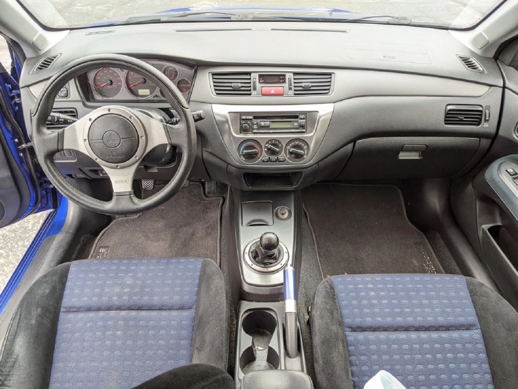 The dashboard and blue-trimmed Recaro front seats of a 2005 Mitsubishi Lancer Evolution VIII