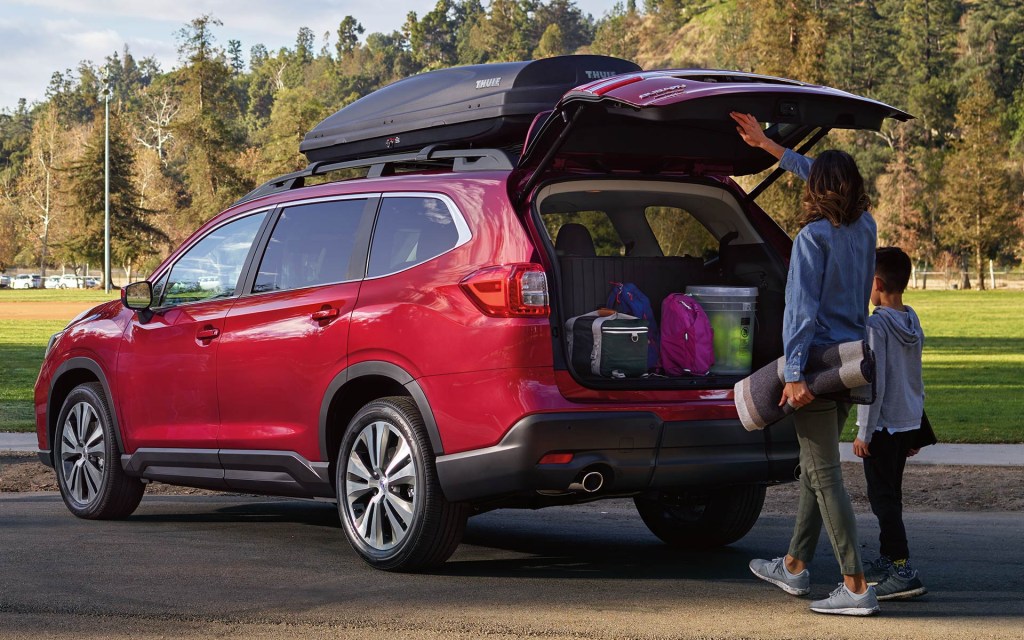 A woman and a child loading luggage in the trunk of a red Subaru Ascent.