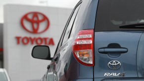 A look at the rear of a blue 2012 Toyota RAV4 with the red Toyota logo in the background