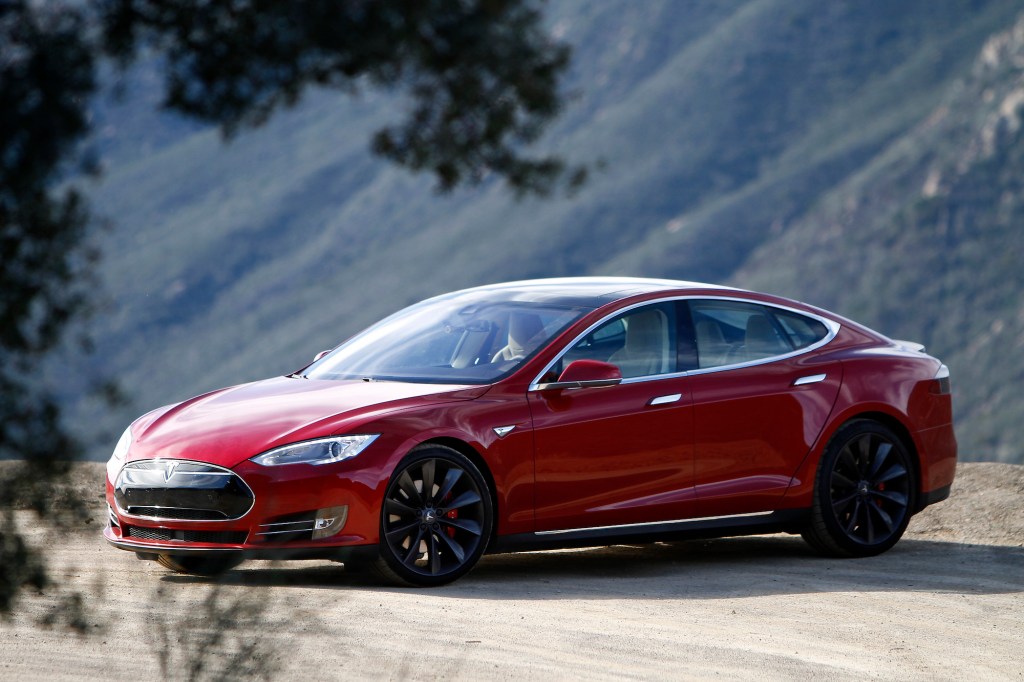 A red A 2015 Tesla Model parked on a dirt road in front of mountains in California S P85D