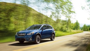 A blue 2016 Subaru Crosstrek driving down a highway road