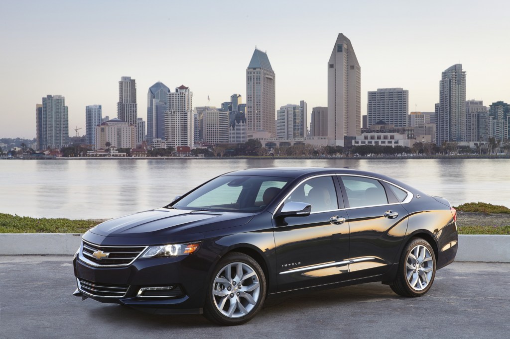 A black 2018 Chevy Impala parked in front the river with the city skyline in the background 