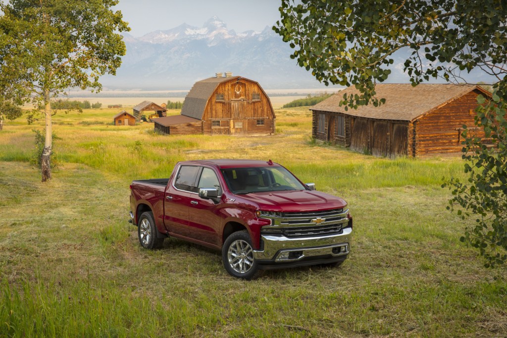 A red 2020 Chevy Silverado LTZ parked in a field with trees in the background