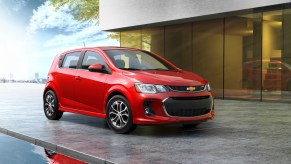 A red 2020 Chevy Sonic parked hatchback parked next to a modern gray house