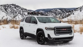 A white 2020 GMC Acadia AT4 parked in the snow in front of mountains