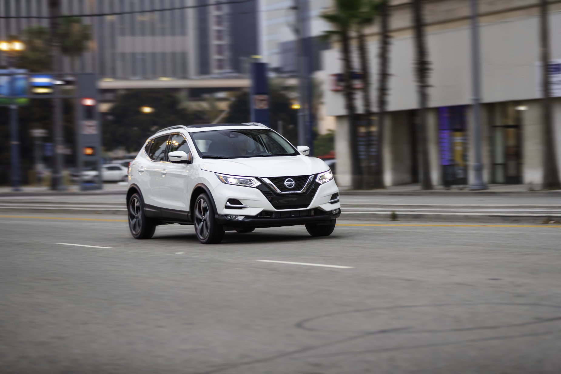 A white 2020 Nissan Rogue Sport driving down a city road