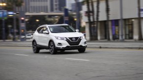 A white 2020 Nissan Rogue Sport driving down a city road