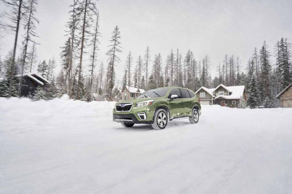 A green 2020 Subaru Forester driving through a snowy road