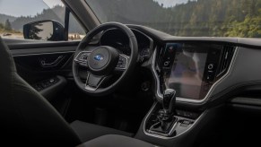 A 2020 Subaru Outback's black interior, showing the steering wheel, gear shifter, and infotainment display
