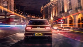 Rear view of a gold 2021 Bentley Bentayga Hybrid on a city street at night