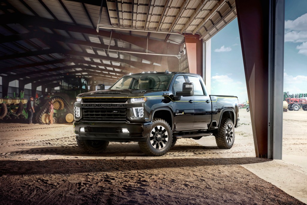 A black 2021 Chevy Silverado HD Carhartt Special Edition parked in a dusty barn with tractors
