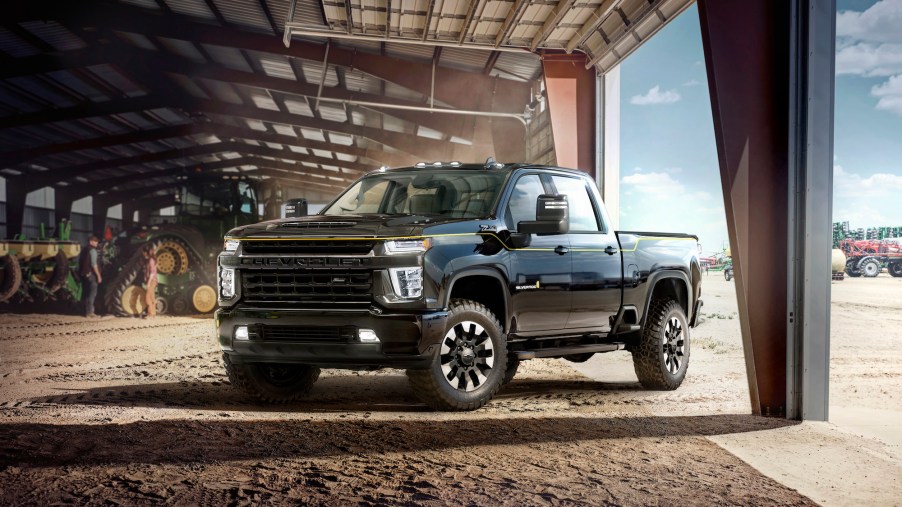 A black 2021 Chevy Silverado HD Carhartt Special Edition parked in a dusty barn with tractors