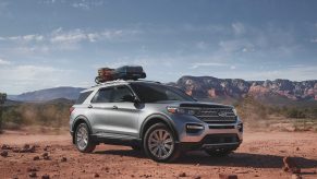 A silver 2021 Ford Explorer with a bag mounted on its roof rack driving down a dirt road