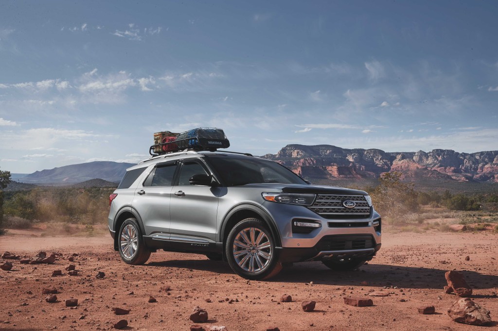 A silver 2021 Ford Explorer with a bag mounted on its roof rack driving down a dirt road