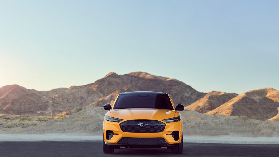 A yellow Ford Mustang Mach-E GT Performance Edition parked on asphalt in front of mountains