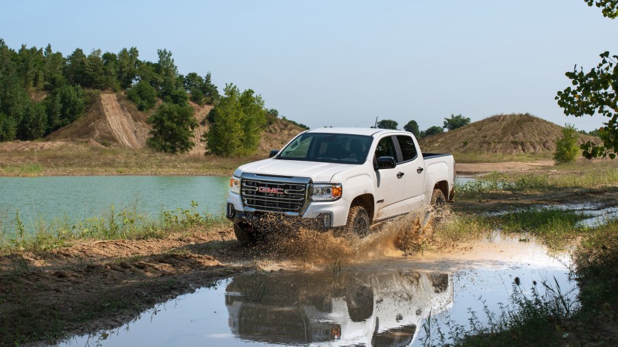 A white 2021 GMC Canyon AT4 Off-Road Performance Edition splashes through muddy water