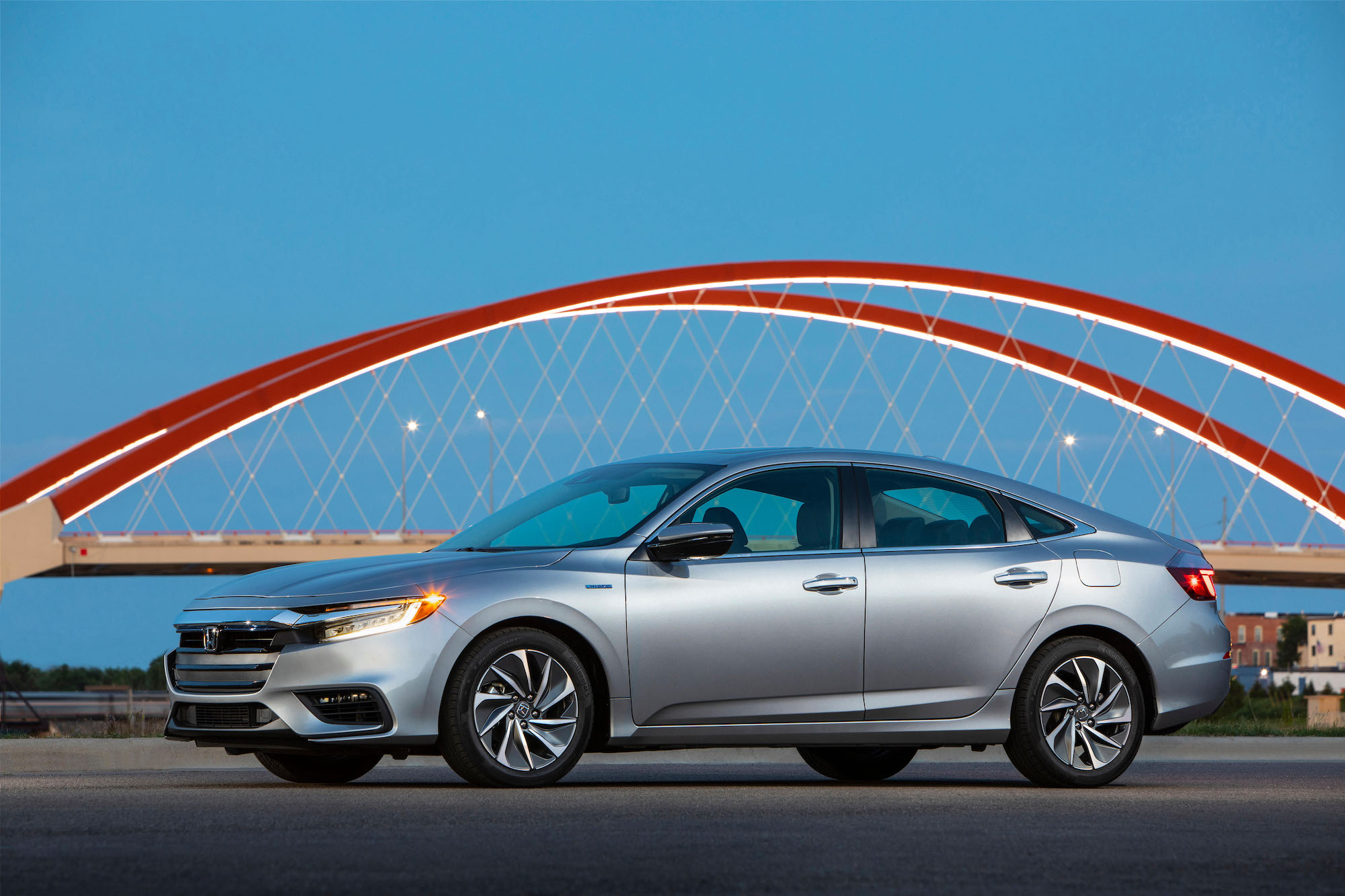 A silver 2021 Honda Insight hybrid sedan parked in front of a red bridge and blue sky