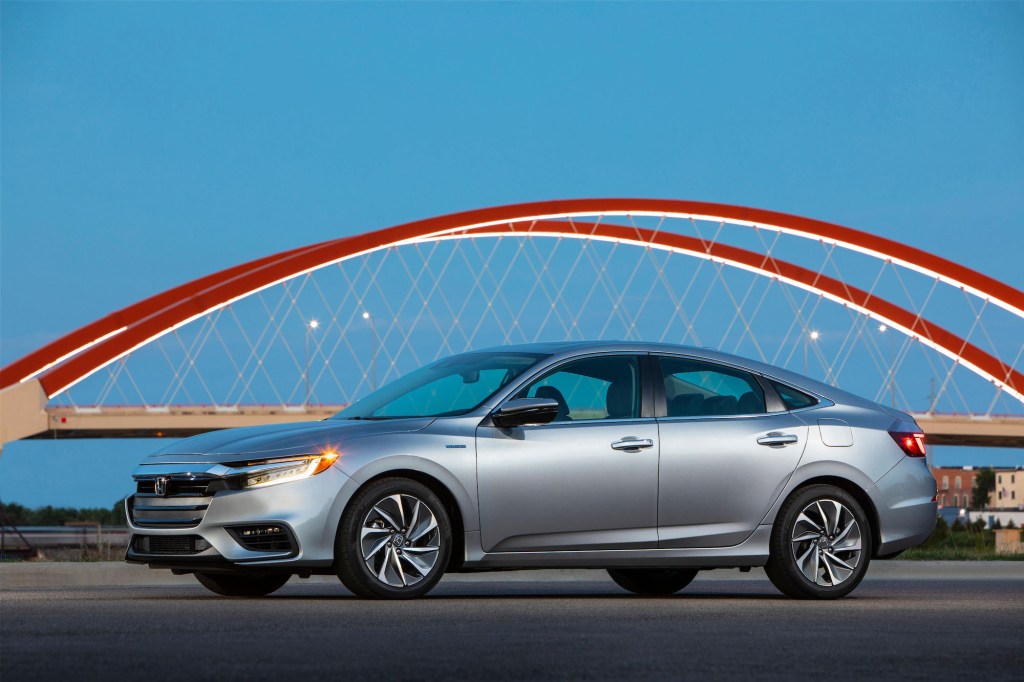 A silver 2021 Honda Insight hybrid sedan parked in front of a red bridge and blue sky