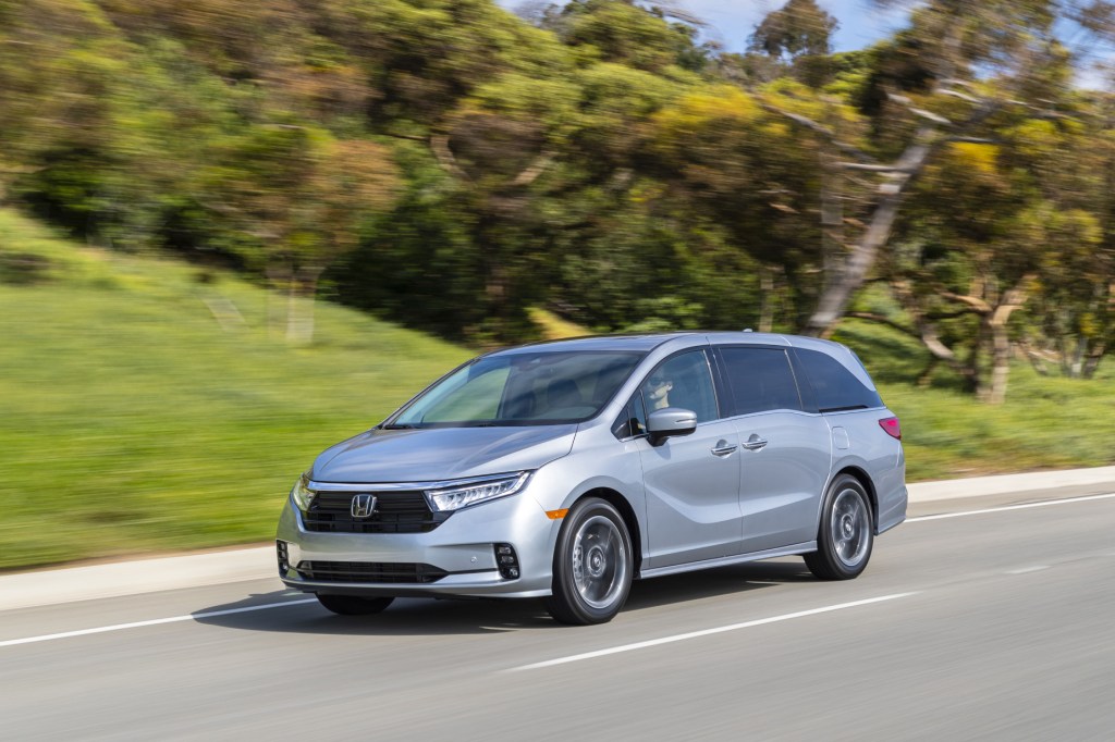 A silver 2021 Honda Odyssey driving down a highway road