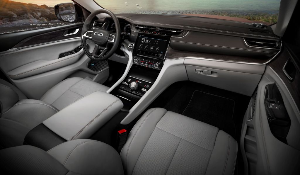 The white front seats and wood-trimmed dash of the 2021 Jeep Grand Cherokee L Overland