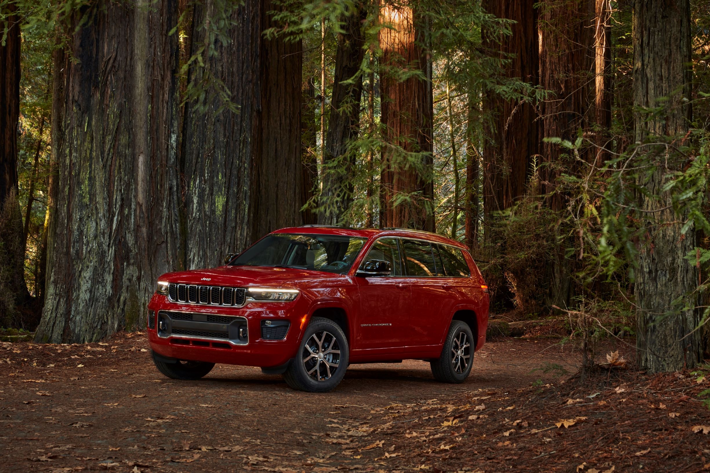 A red 2021 Jeep Grand Cherokee L Overland in a forest
