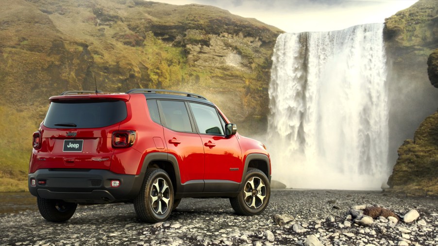 A red 2021 Jeep Renegade subcompact SUV parked next to a waterfall