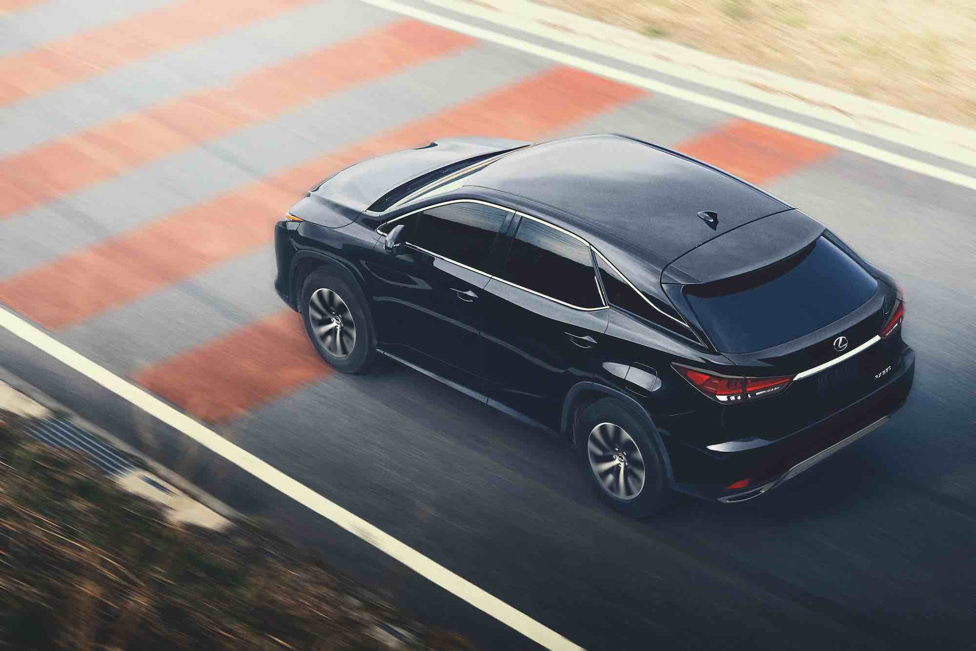 A black 2021 Lexus RX350 travels on a paved strip painted with red lines