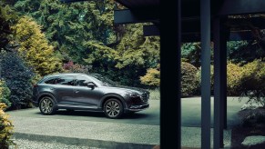 A metallic dark-gray 2021 Mazda CX-9 midsize crossover SUV sits in a home's driveway