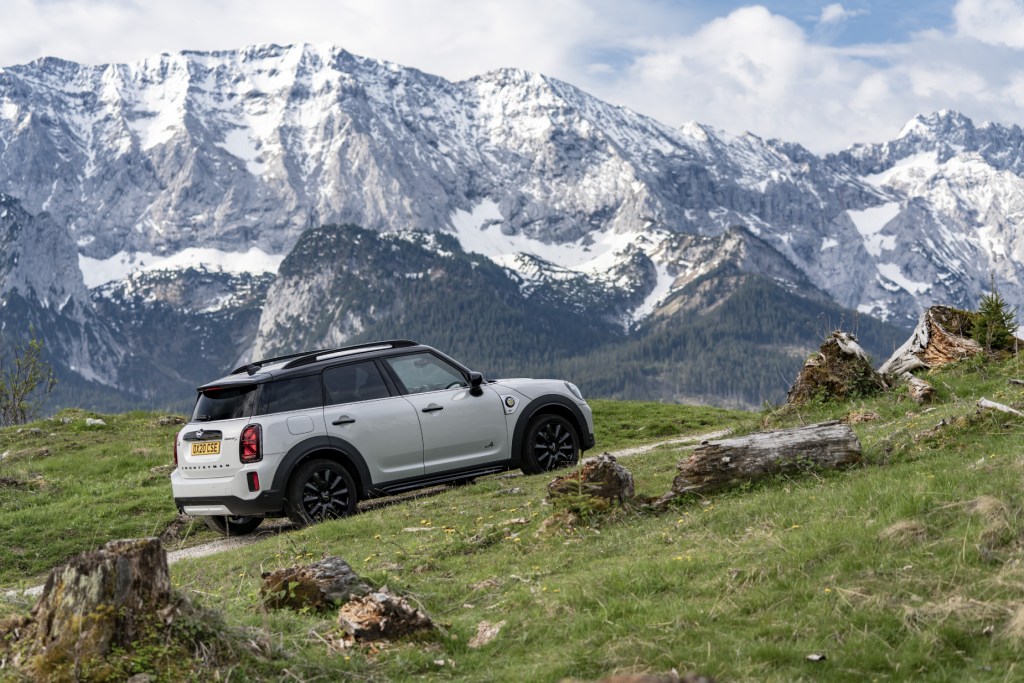 A white 2021 Mini Countryman driving uphill with a mountain in the background