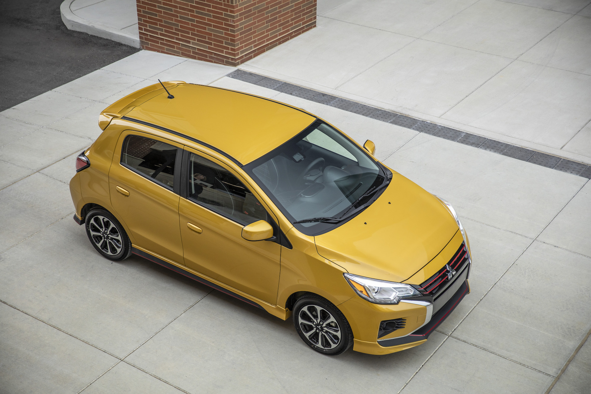 A 2021 Mitsubishi Mirage in Sand Yellow parked on a concrete slab