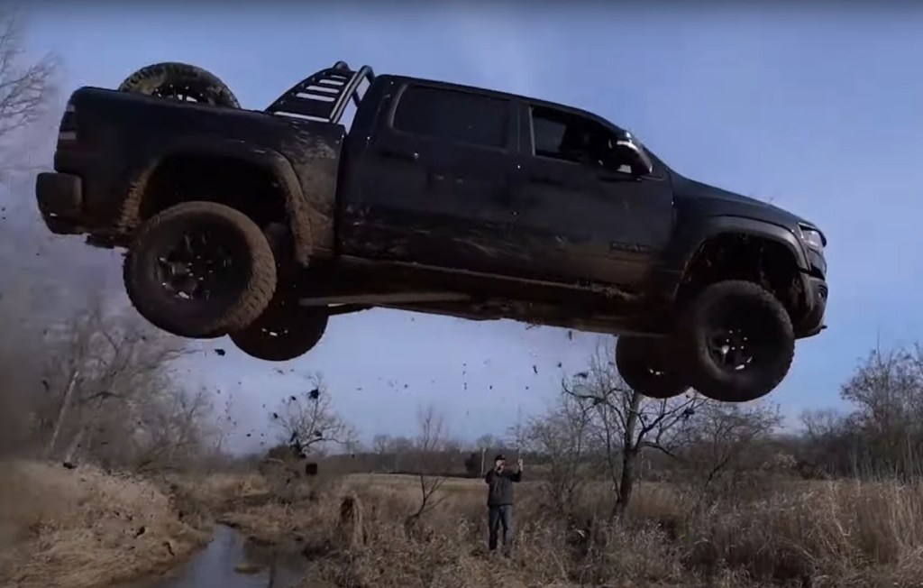 A black 2021 Ram 1500 TRX off-road pickup runs off the end of a ramp.