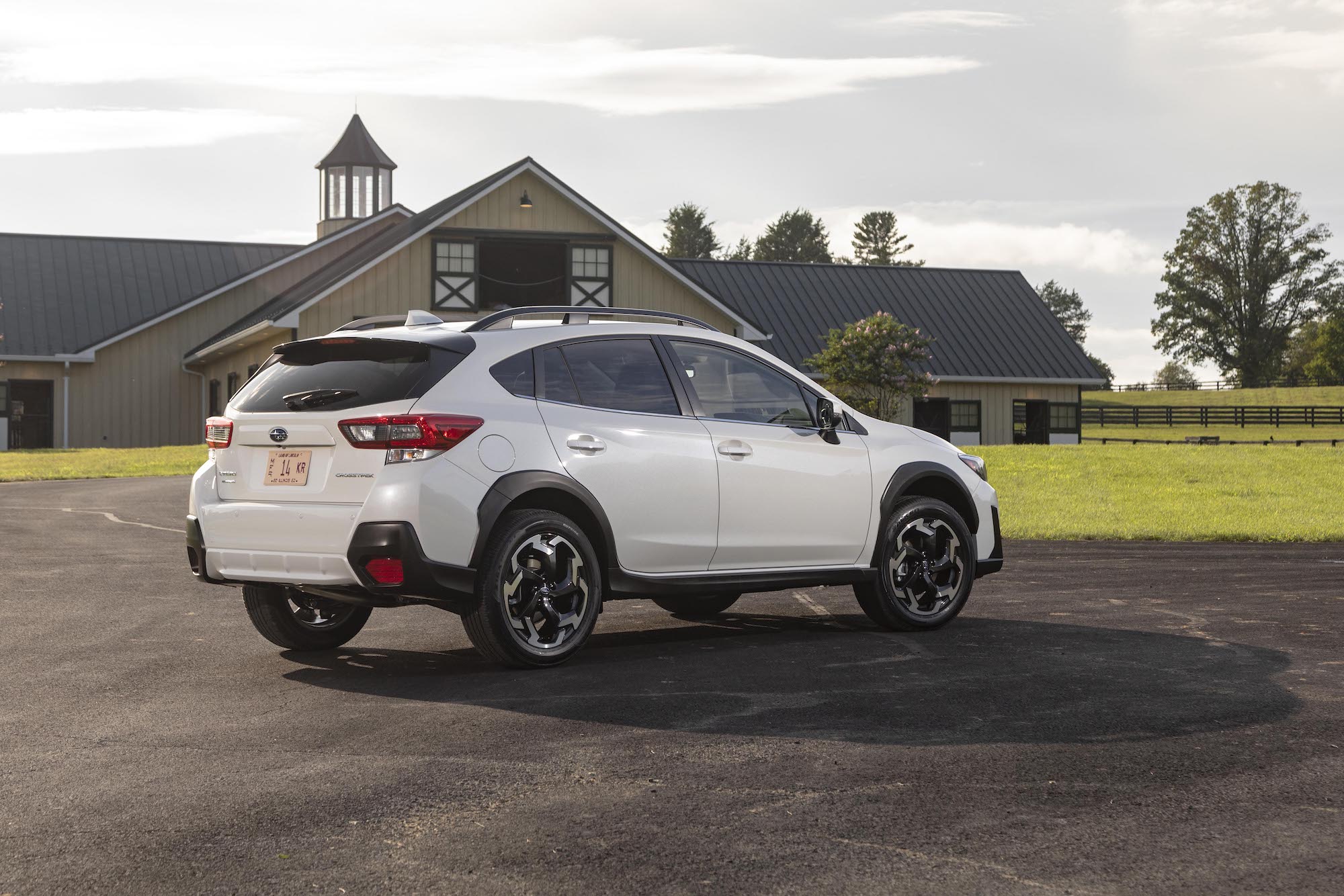 A 2021 Subaru Crosstrek Limited in Crystal White Pearl parked on gravel in front of a barn