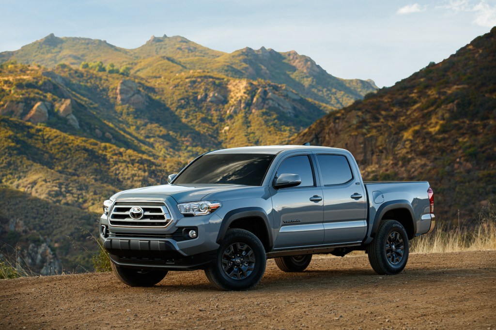 A gray 2021 Toyota Tacoma Trail Edition parked on brown dirt in front of green and brown mountains
