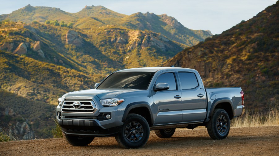 A gray 2021 Toyota Tacoma Trail Edition parked on brown dirt in front of green and brown mountains