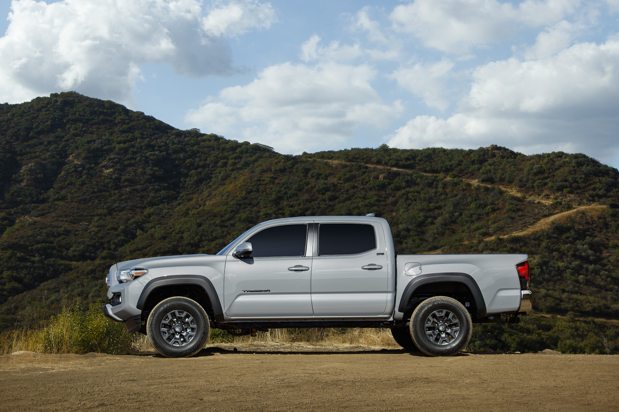 A silver 2021 Toyota Tacoma Trail Edition parked on dirt in front of a mountain
