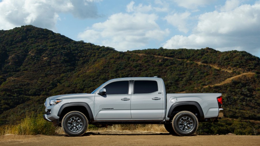 A silver 2021 Toyota Tacoma Trail Edition parked on dirt in front of a mountain