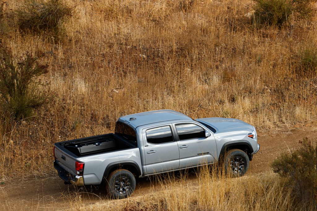 A silver 2021 Toyota Tacoma Trail Edition parked on a dirt road amid brown weeds