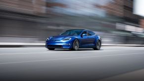 A refreshed blue 2021 Tesla Model S driving down the street.