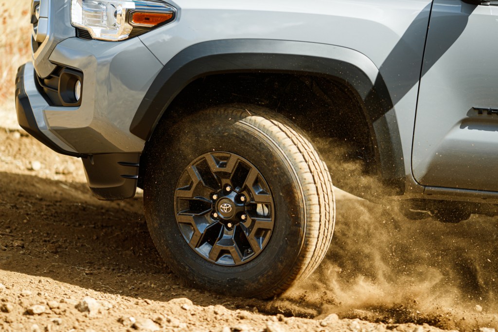 The front left tire of a 2021 Toyota Tacoma kicking up dirt while driving off-road